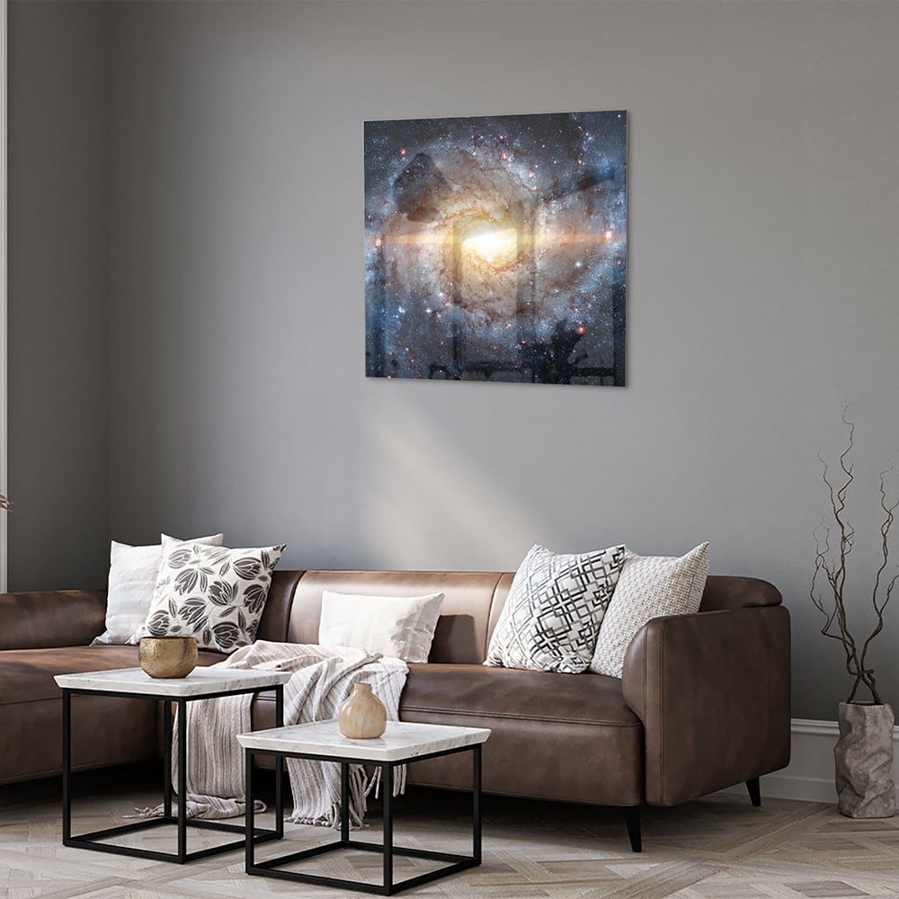 Glazen schilderij van een sterrenstelsel aan de muur in een lichte woonkamer.