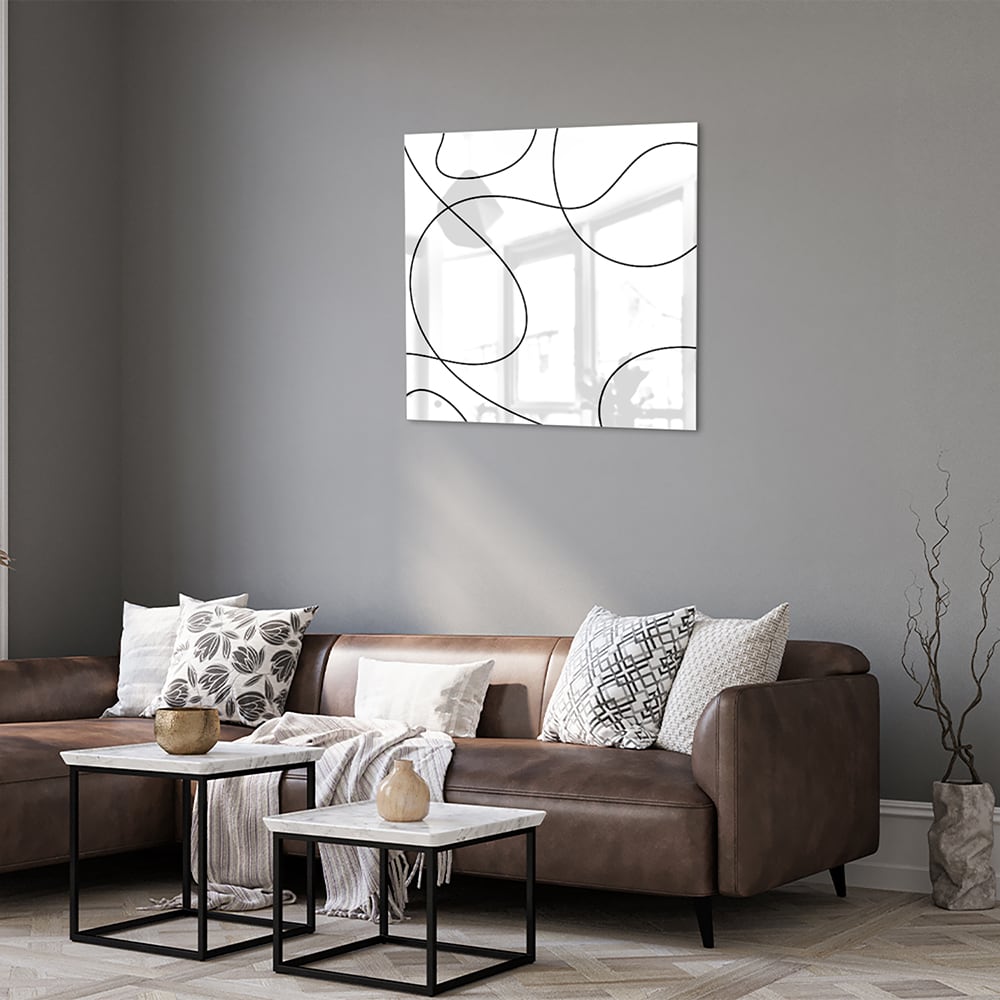 Glazen schilderij met elegante zwarte lijnen in een moderne woonkamer.