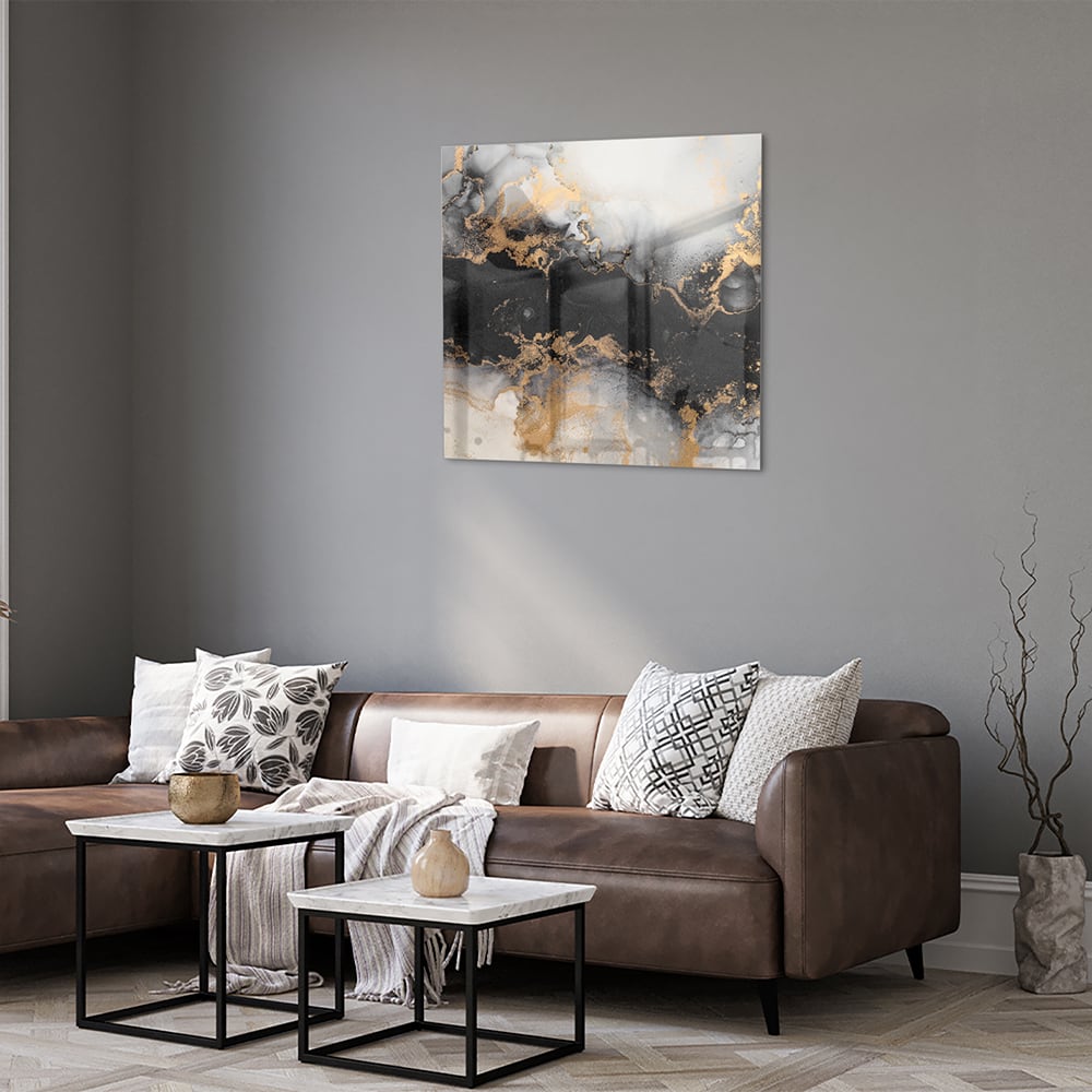 Glazen schilderij met zwarte en gouden abstracte patronen aan de muur boven een houten kast.
