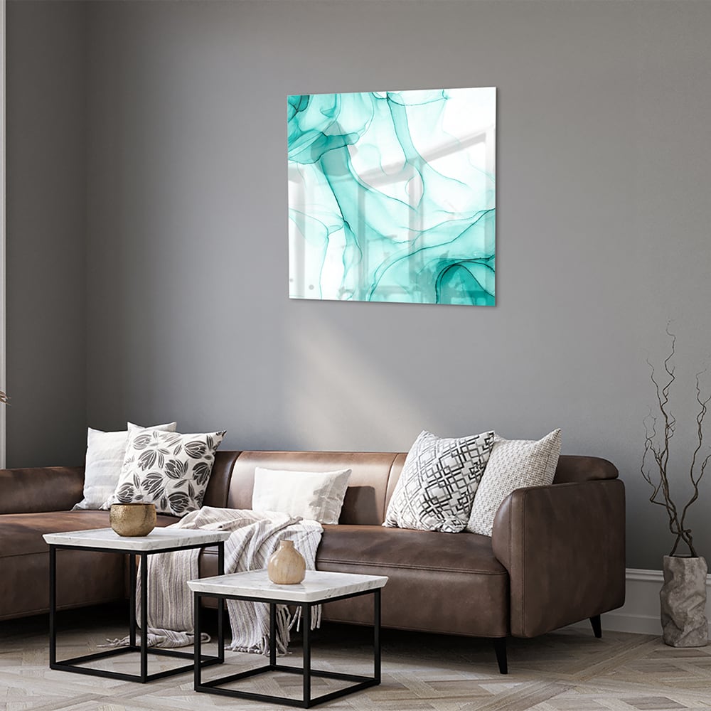 Lichtblauw abstract glazen schilderij aan de muur boven een houten meubel.