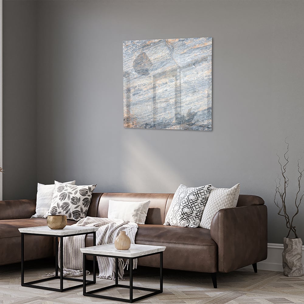 Abstract glazen schilderij met blauwe en oranje tinten aan de muur in een moderne woonkamer.