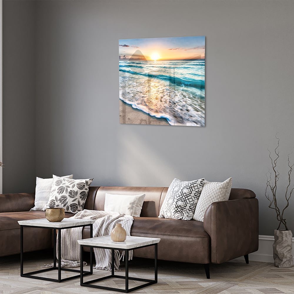 Glazen schilderij van een zonsondergang boven de zee, met kalme golven en zand.