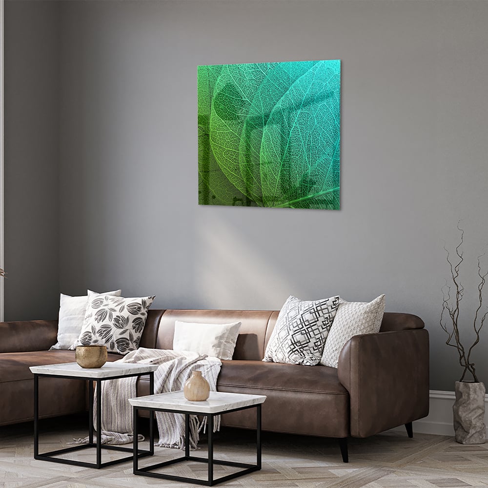Glas schilderij met de structuur van groene bladeren aan een muur.