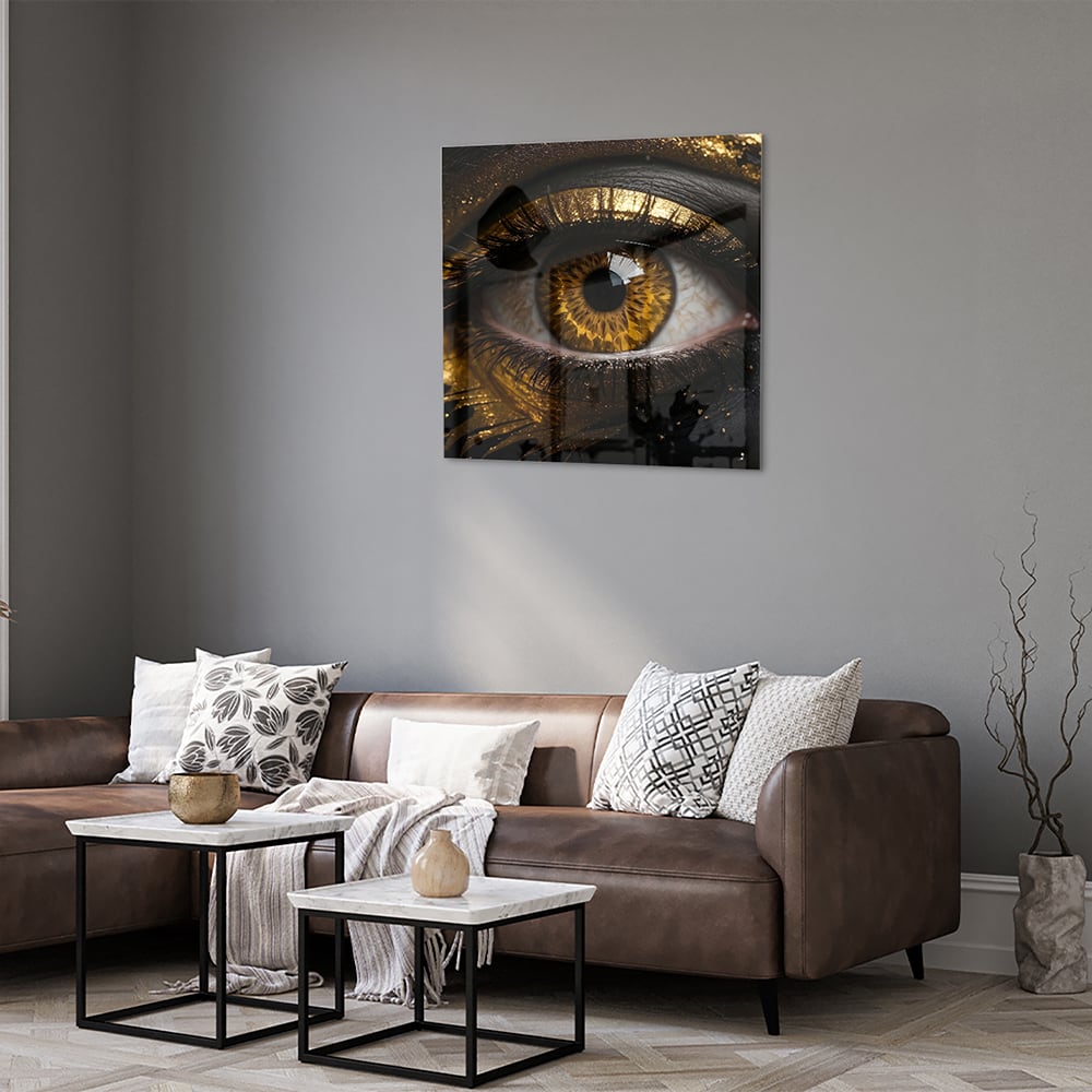 Glazen schilderij van een gouden oog op een zwarte achtergrond, hangt aan de muur.