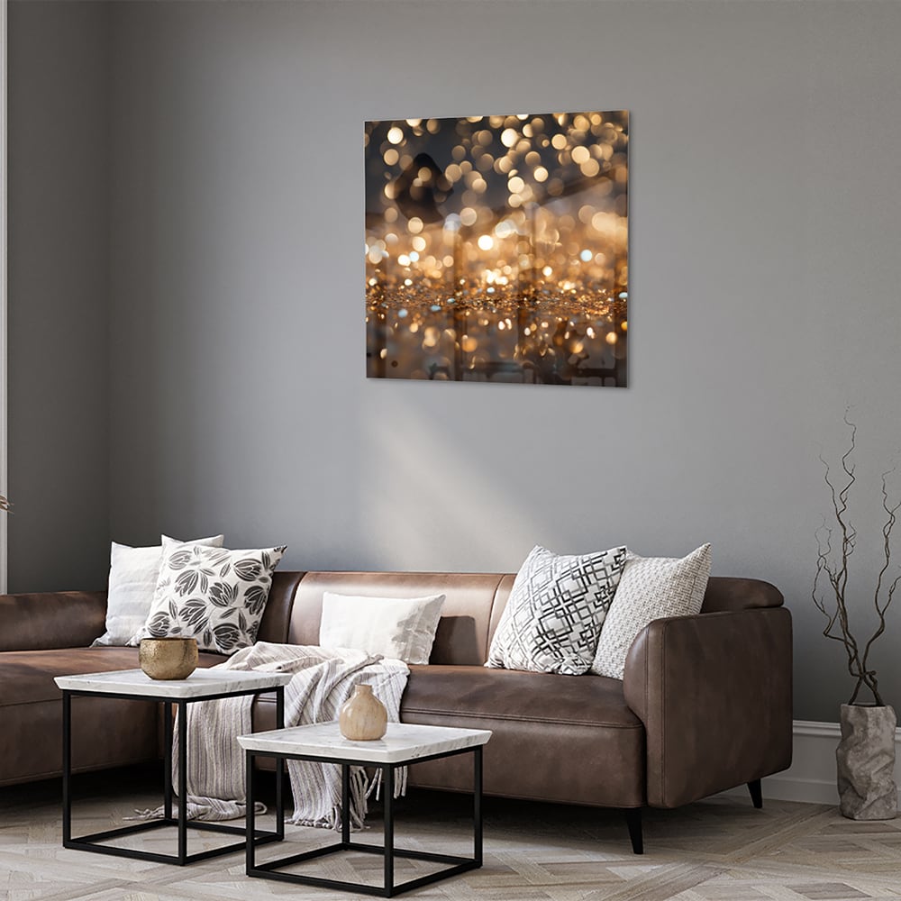 Glazen schilderij met gouden bokeh-effect aan de muur in een moderne woonkamer.