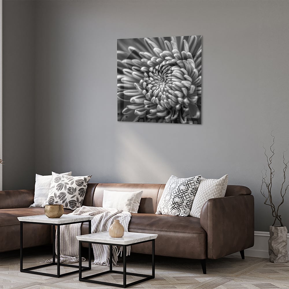 Zwart-wit glas schilderij van een kronkelige bloem aan de muur.