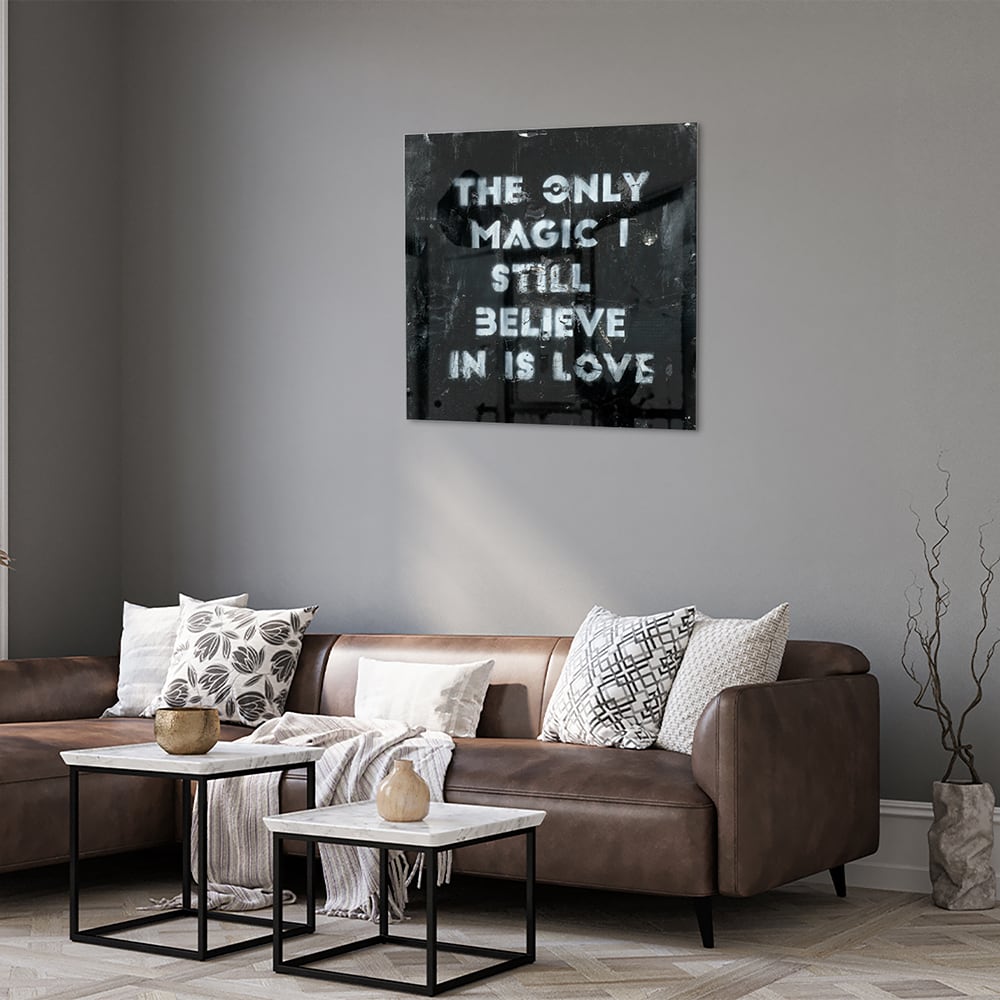 Glazen schilderij met de tekst 'The only magic I still believe in is love', hangt aan de muur in een lichte woonkamer.