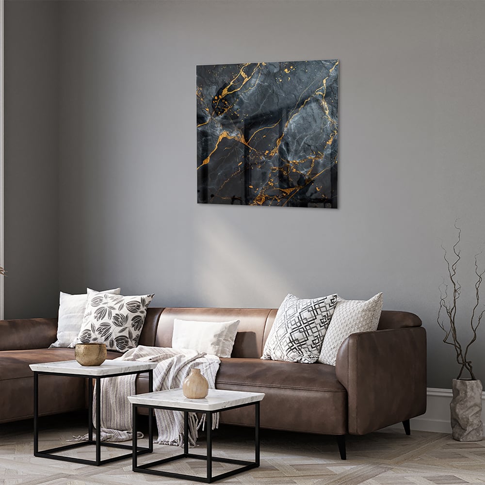 Glazen schilderij met marmerlook in zwart met gouden details aan de muur.