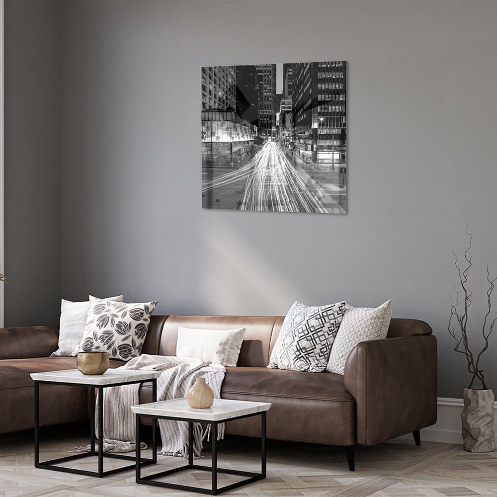 Glazen schilderij met stadslichten in zwart-wit boven een moderne meubelset.