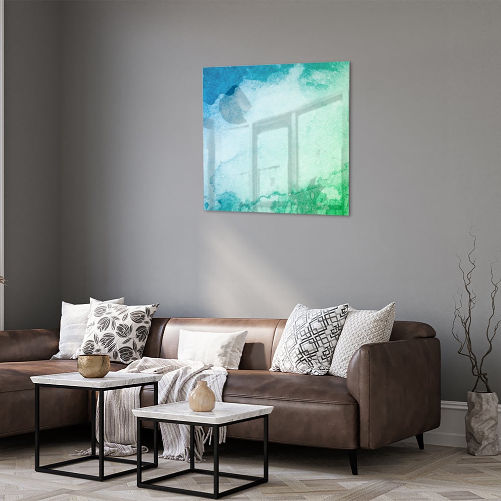 Abstract glazen schilderij in diverse tinten blauw en groen aan de muur.