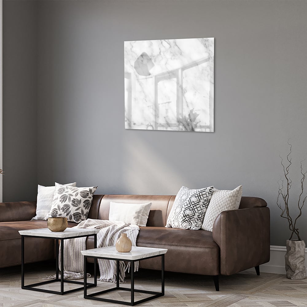Glazen schilderij met marmer effect boven een houten meubel in een lichte kamer.