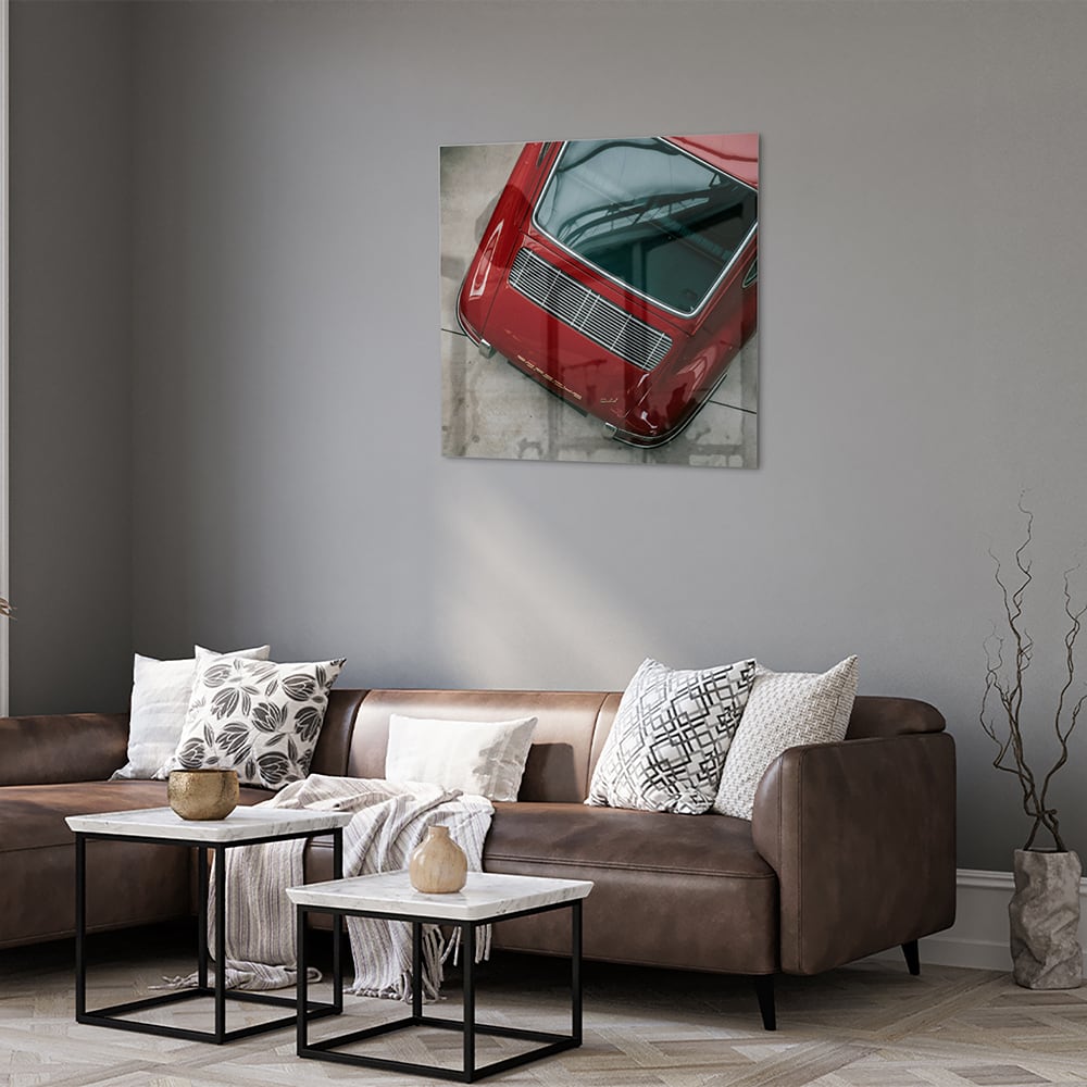 Glazen schilderij van een bovenaf gezien rode auto op een muur.