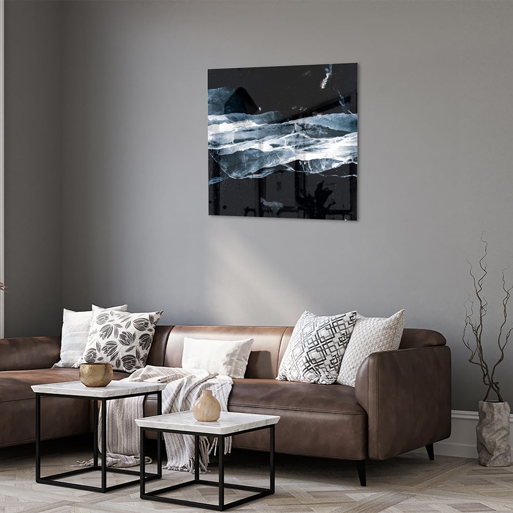 Abstract glazen schilderij in donkere kleuren met blauwe accenten, hangt aan de muur.