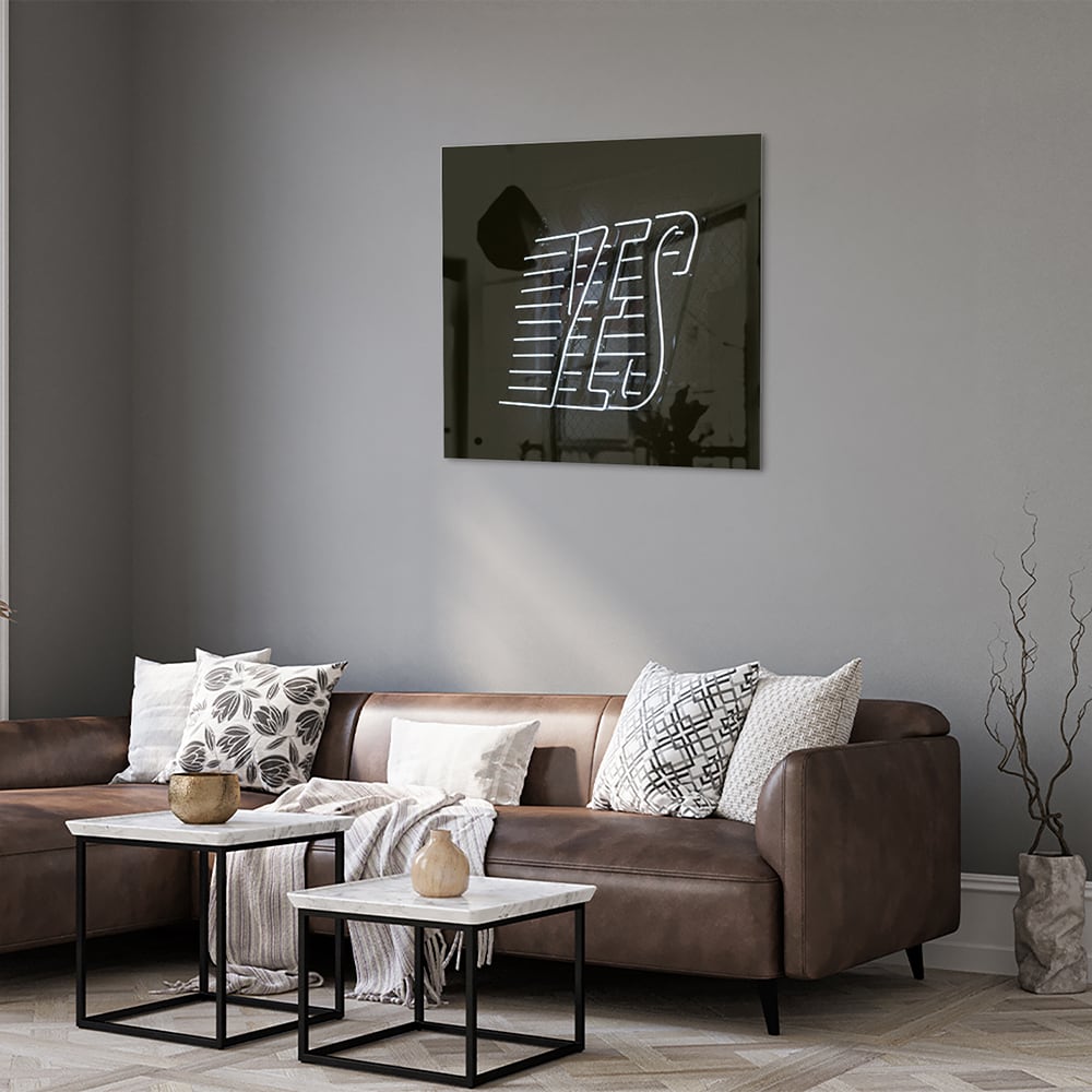 Glazen schilderij met 'YES' text in zwart en wit, hangend aan de muur.