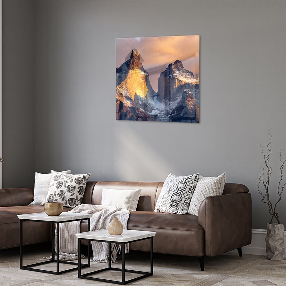 Een glazen schilderij van majestueuze bergen met gouden ochtendlicht
