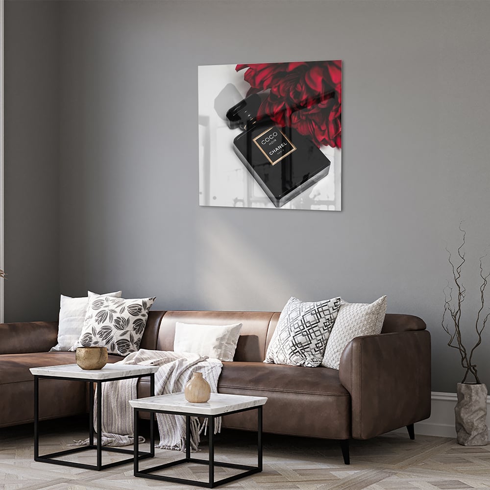 Glazen schilderij van parfumfles met rode bloemen op een witte muur