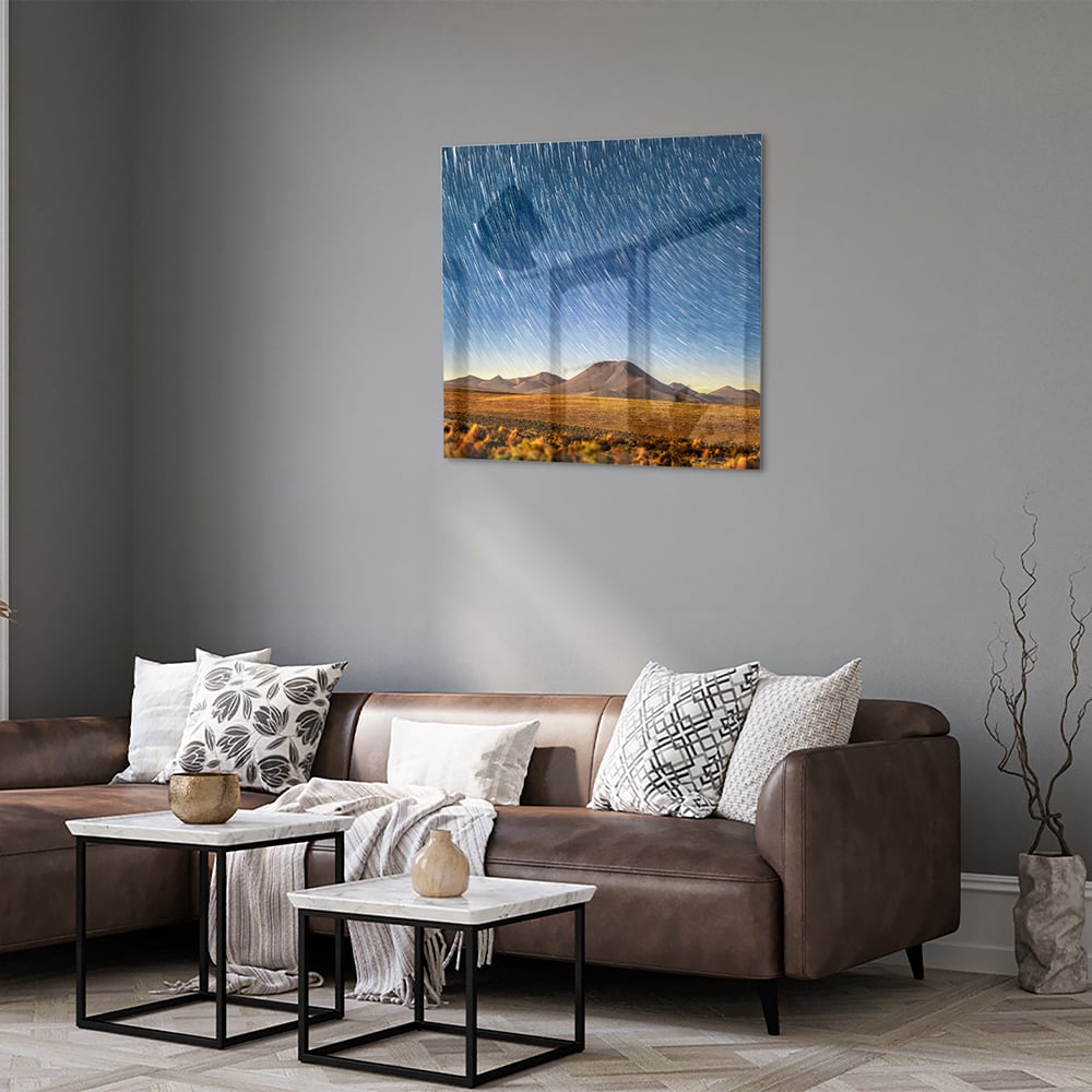 Glazen schilderij met sterrenhemel boven bergen, hangend aan de muur.