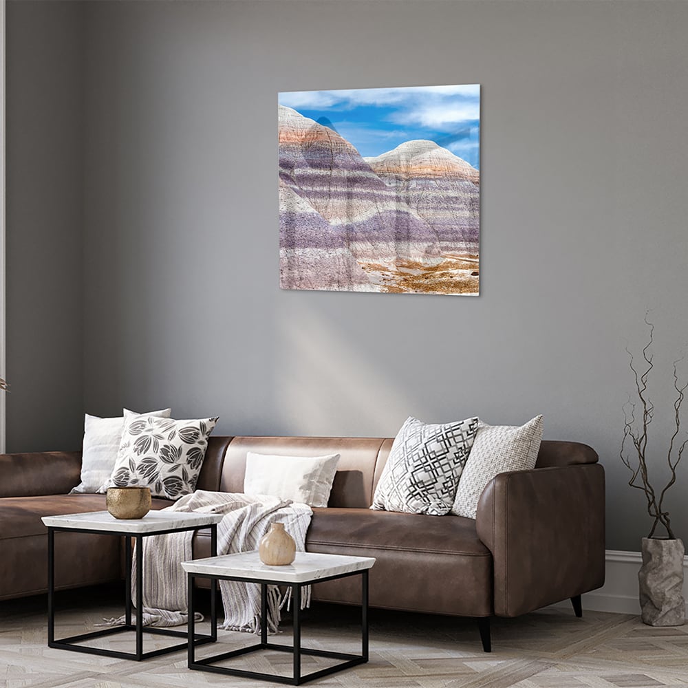 Glazen schilderij van bergen met een blauwe lucht in een moderne woonkamer.