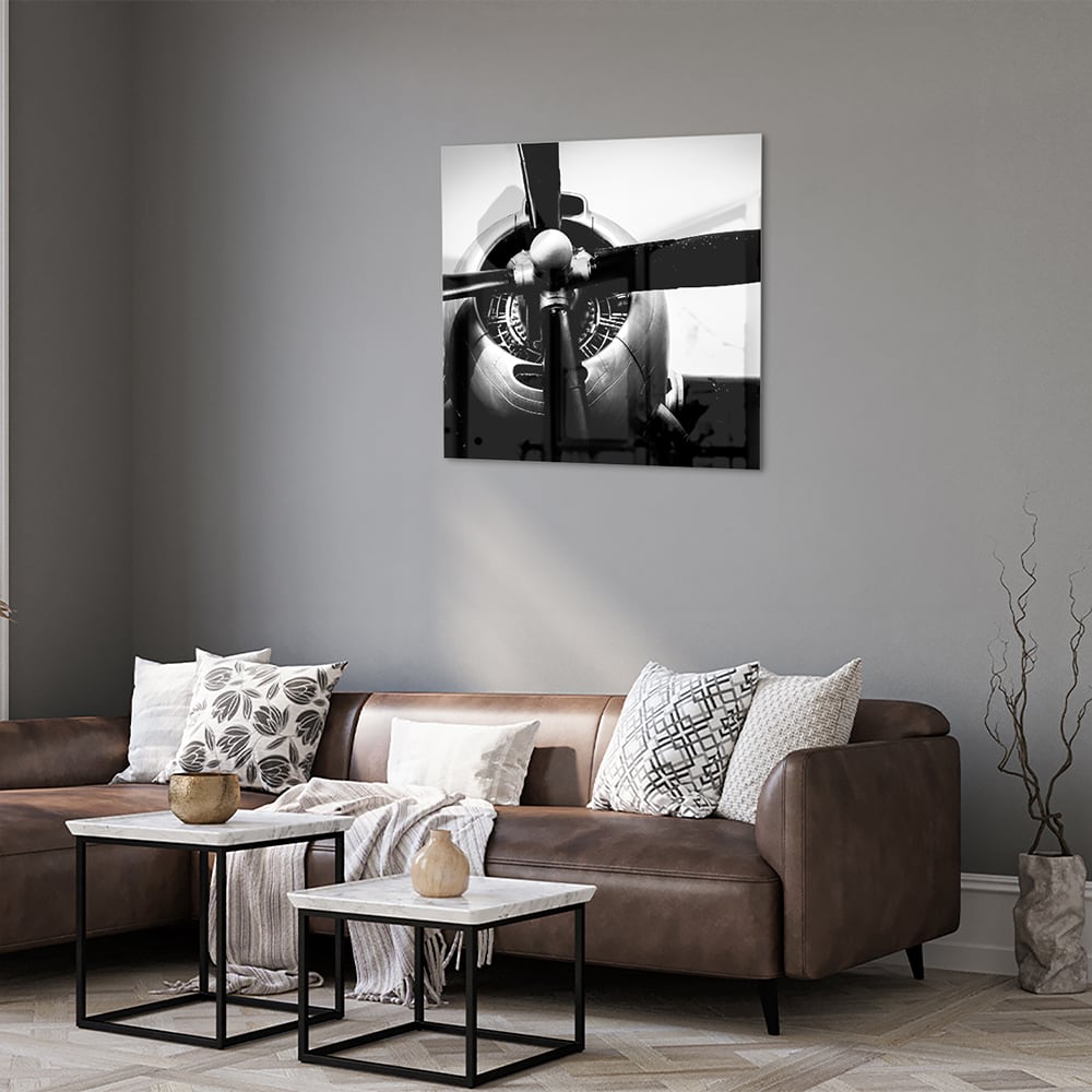 Zwart-wit glazen schilderij van een vintage vliegtuigpropeller tegen een lichte muur.