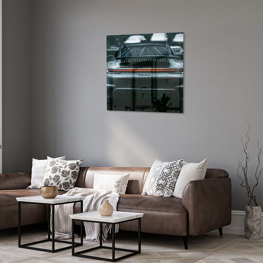 Glazen schilderij van een sportwagen aan de muur in een lichte woonkamer.