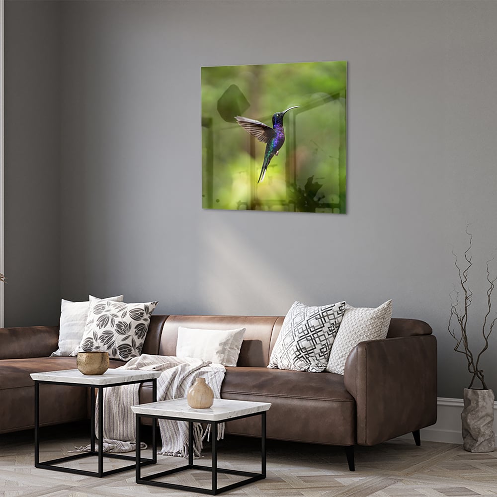 Een glazen schilderij van een kolibrie die vloog voor een groene achtergrond in een lichte kamer.