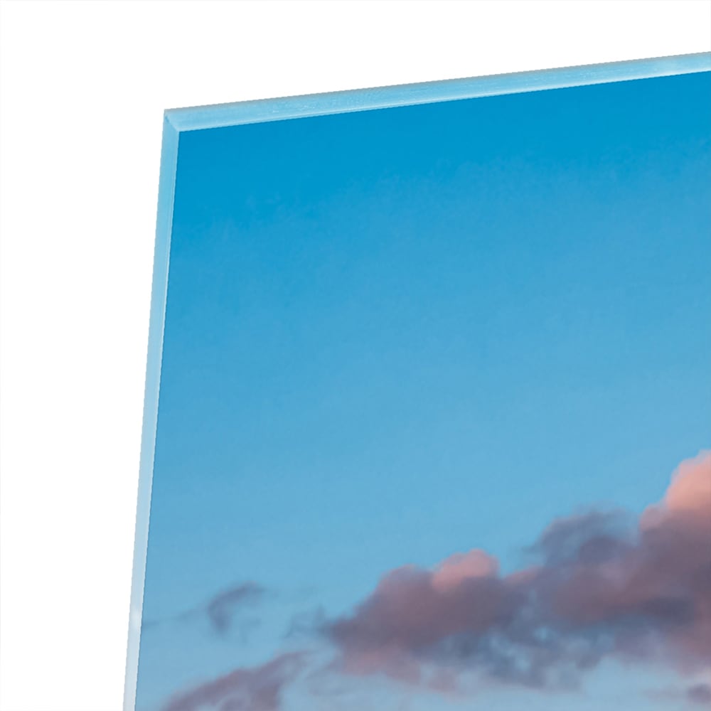 Glazen schilderij van bergen bij zonsopgang in een lichte woonkamer.