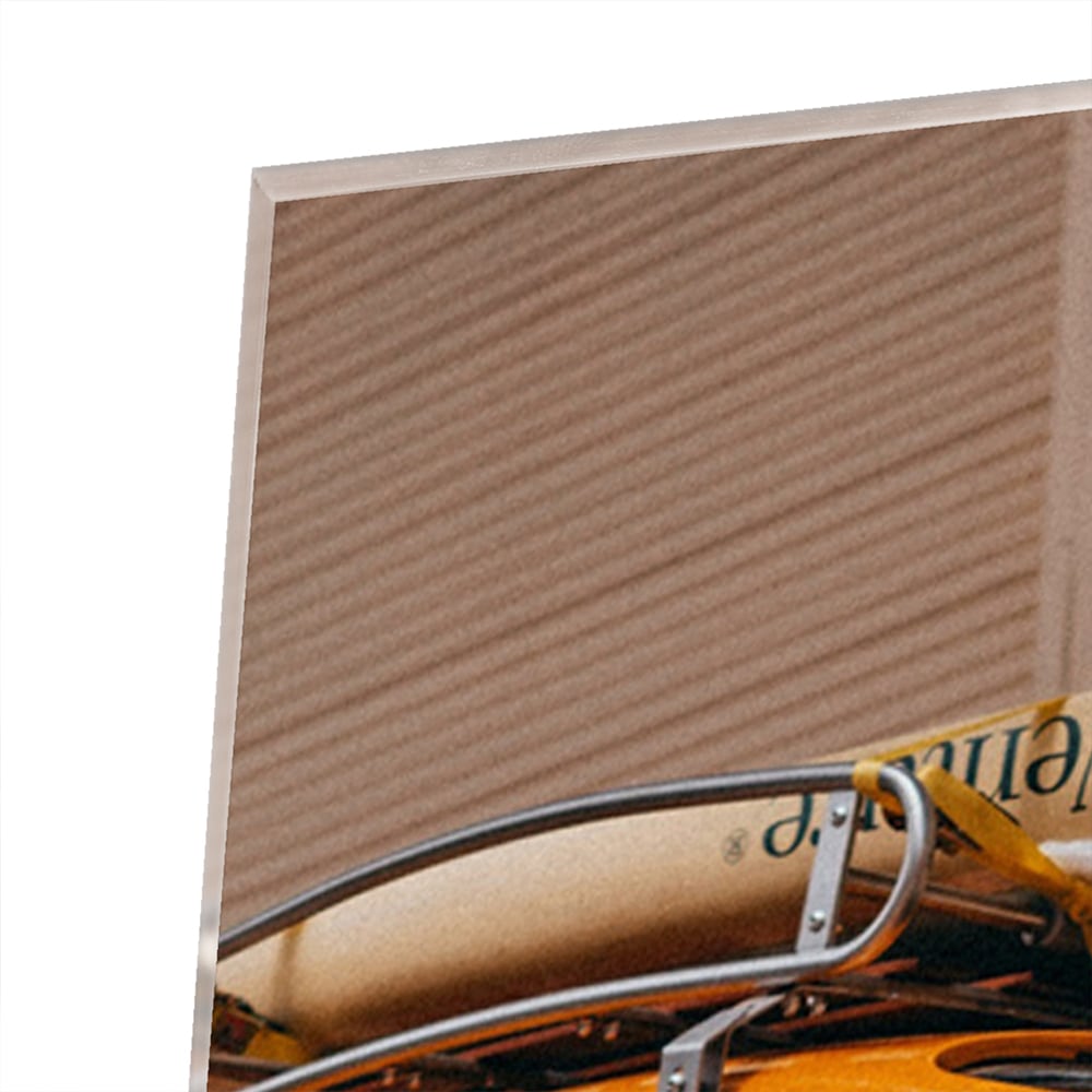 Een glazen schilderij van een oranje auto met een surfbord op het dak, gepresenteerd in een moderne woonkamer.
