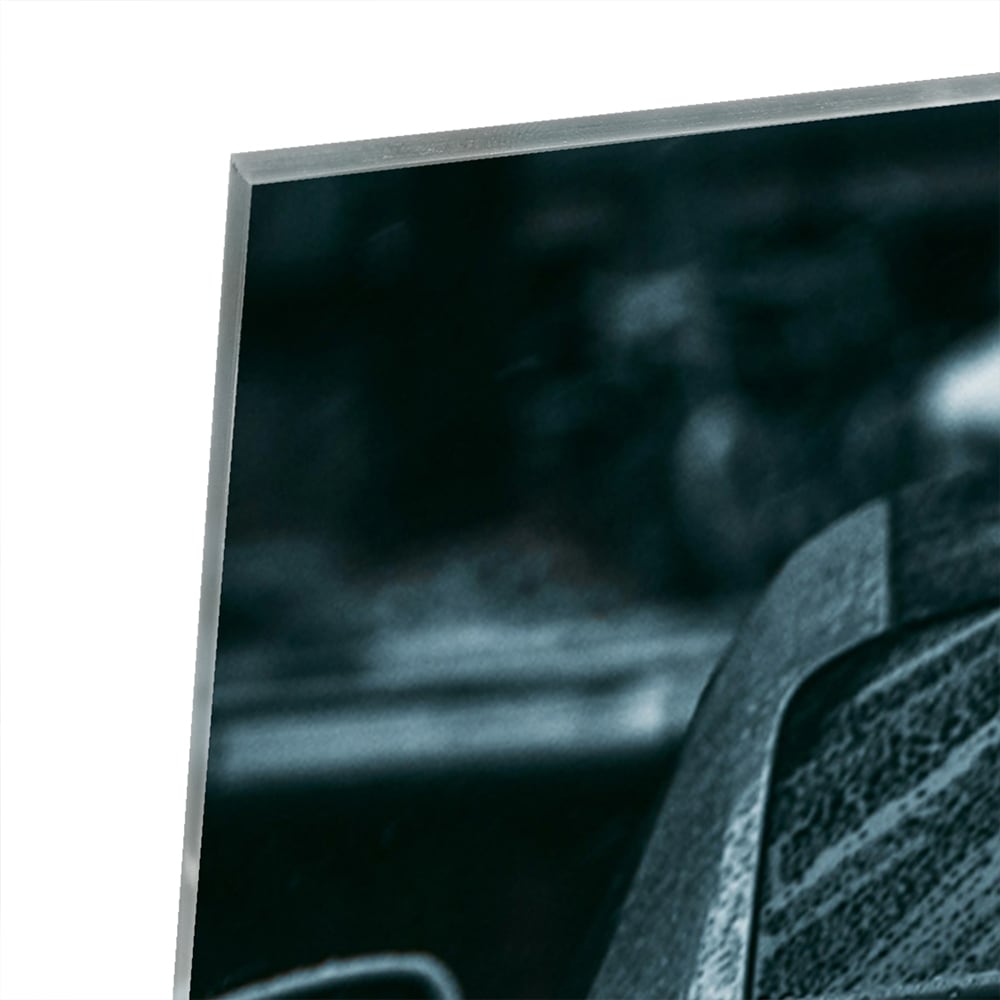 Glazen schilderij van een sportwagen aan de muur in een lichte woonkamer.