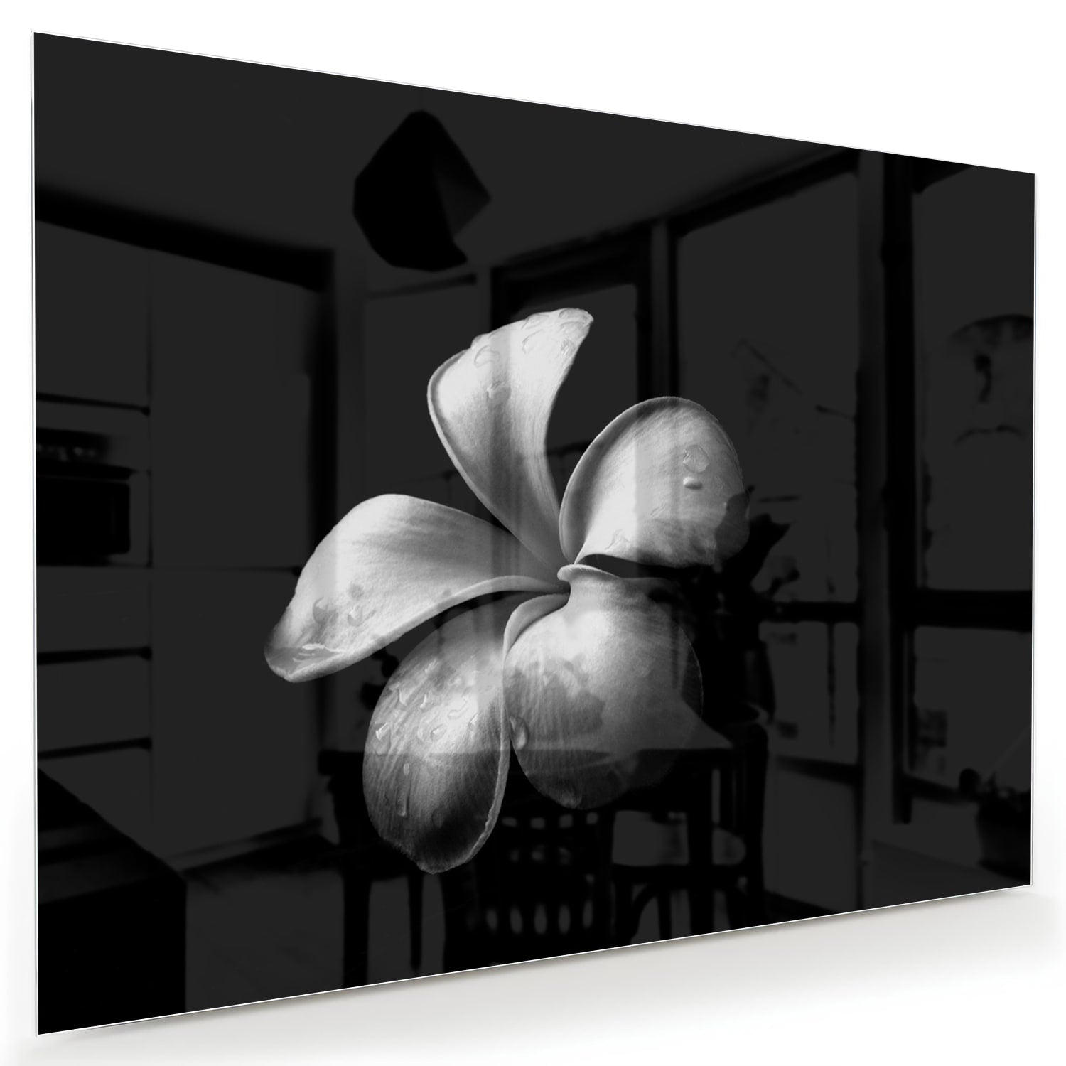 Zwart glazen schilderij met bloemmotief boven een houten kast in een lichte kamer.
