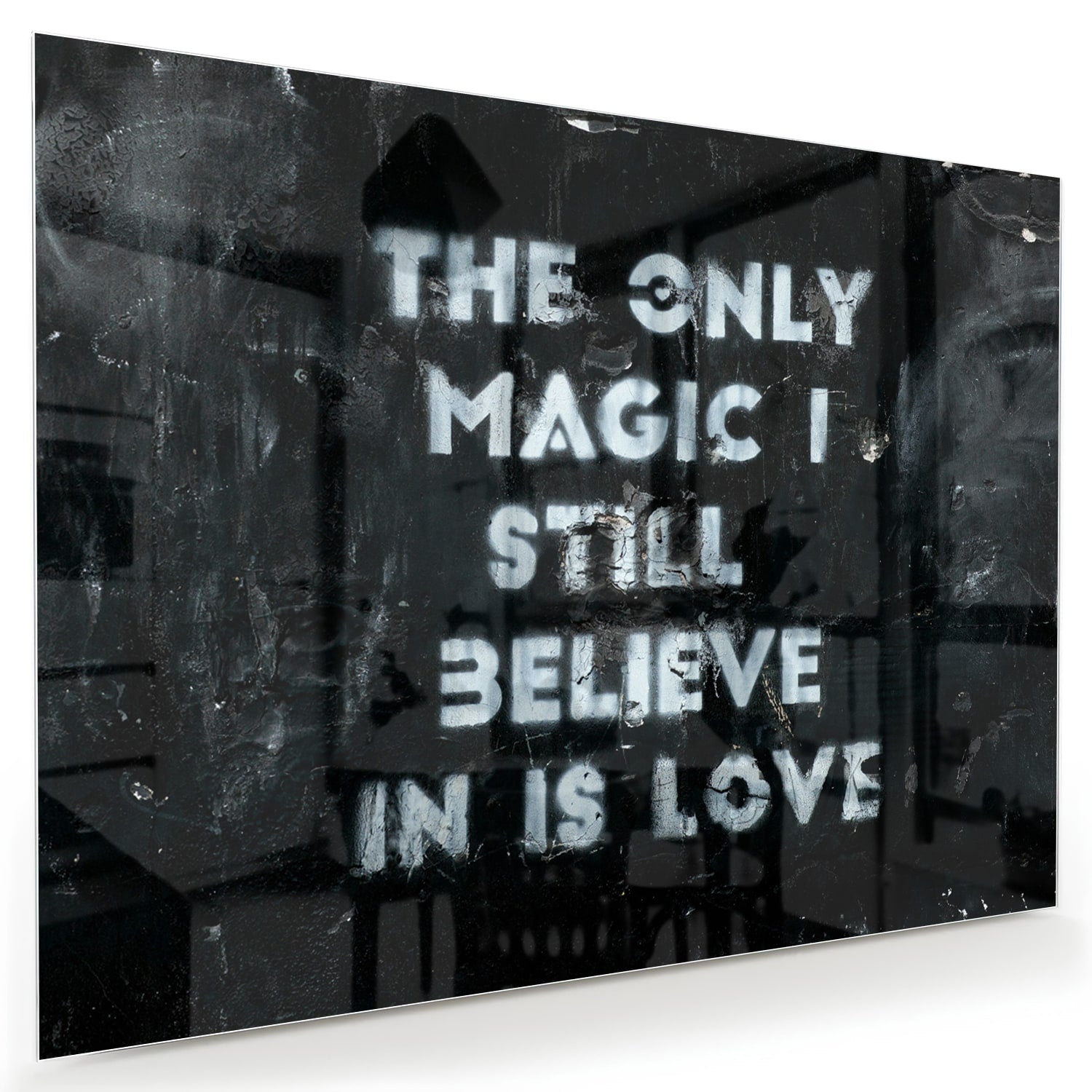 Glazen schilderij met de tekst 'The only magic I still believe in is love', hangt aan de muur in een lichte woonkamer.