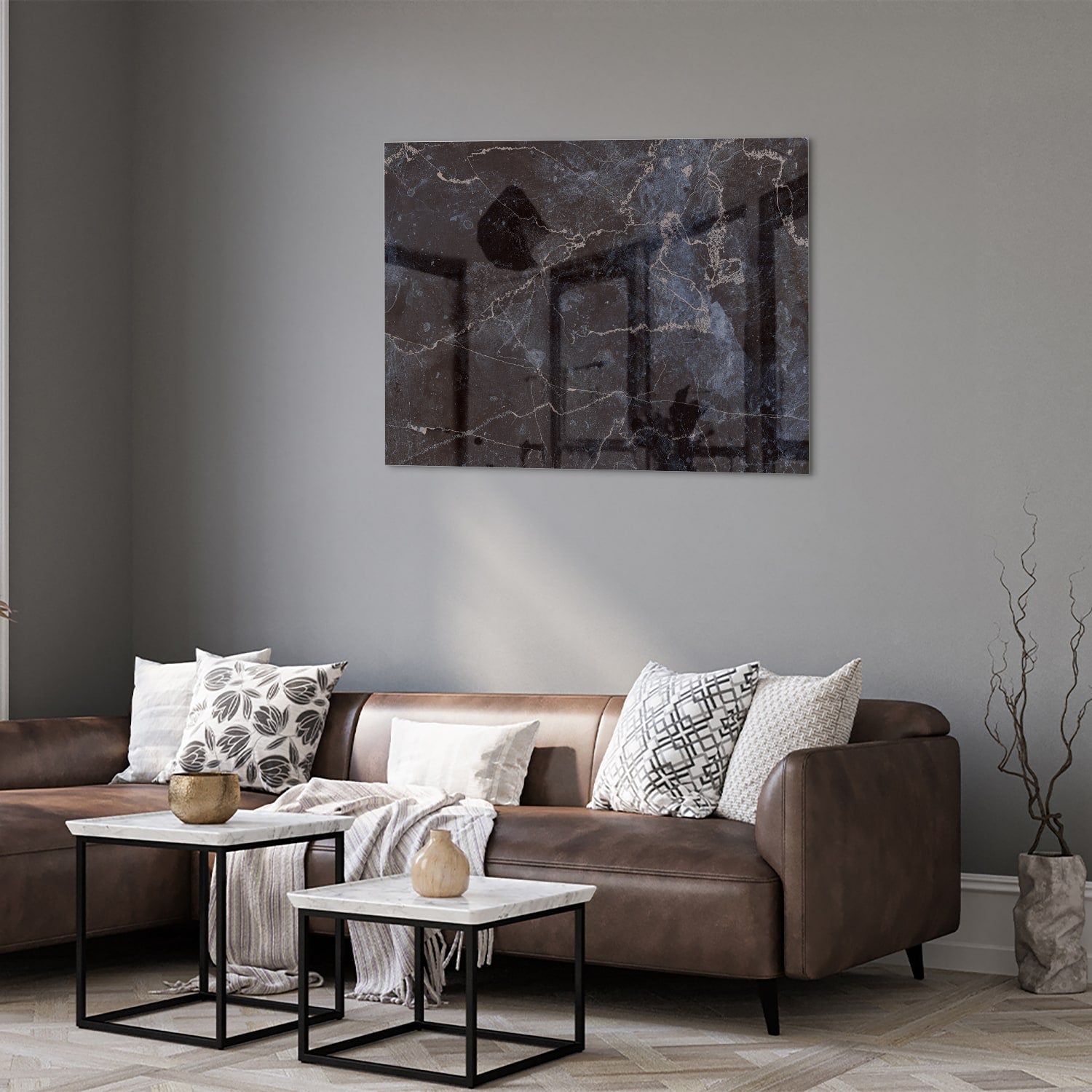 Glazen schilderij met donker marmerlook aan een lichte muur in een moderne woonkamer.