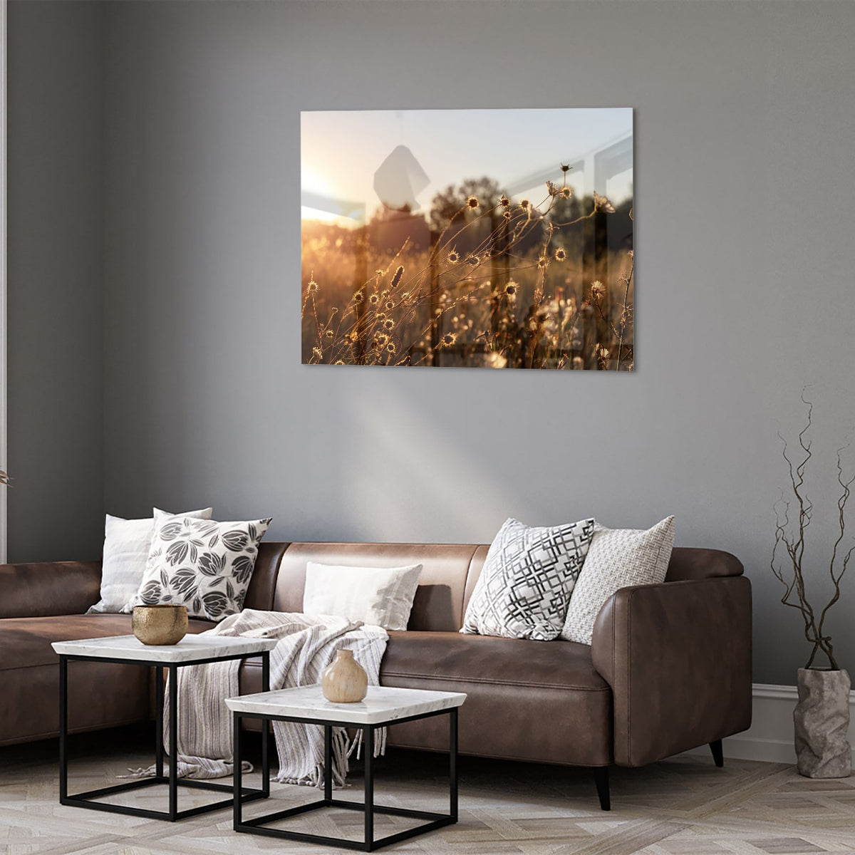 Glazen schilderij van een zonsondergang met bloeiende bloemen, hangend aan een witte muur.