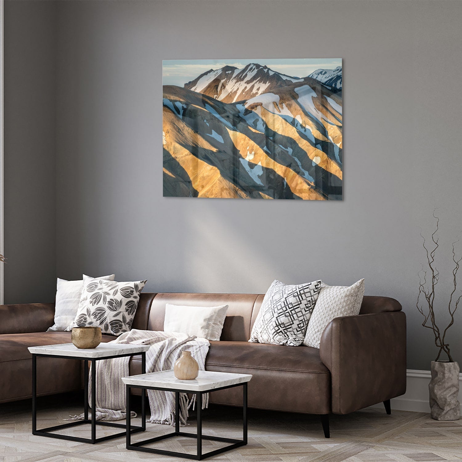 Glazen schilderij van bergen in blauw en goud, hanging in een stijlvolle kamer.