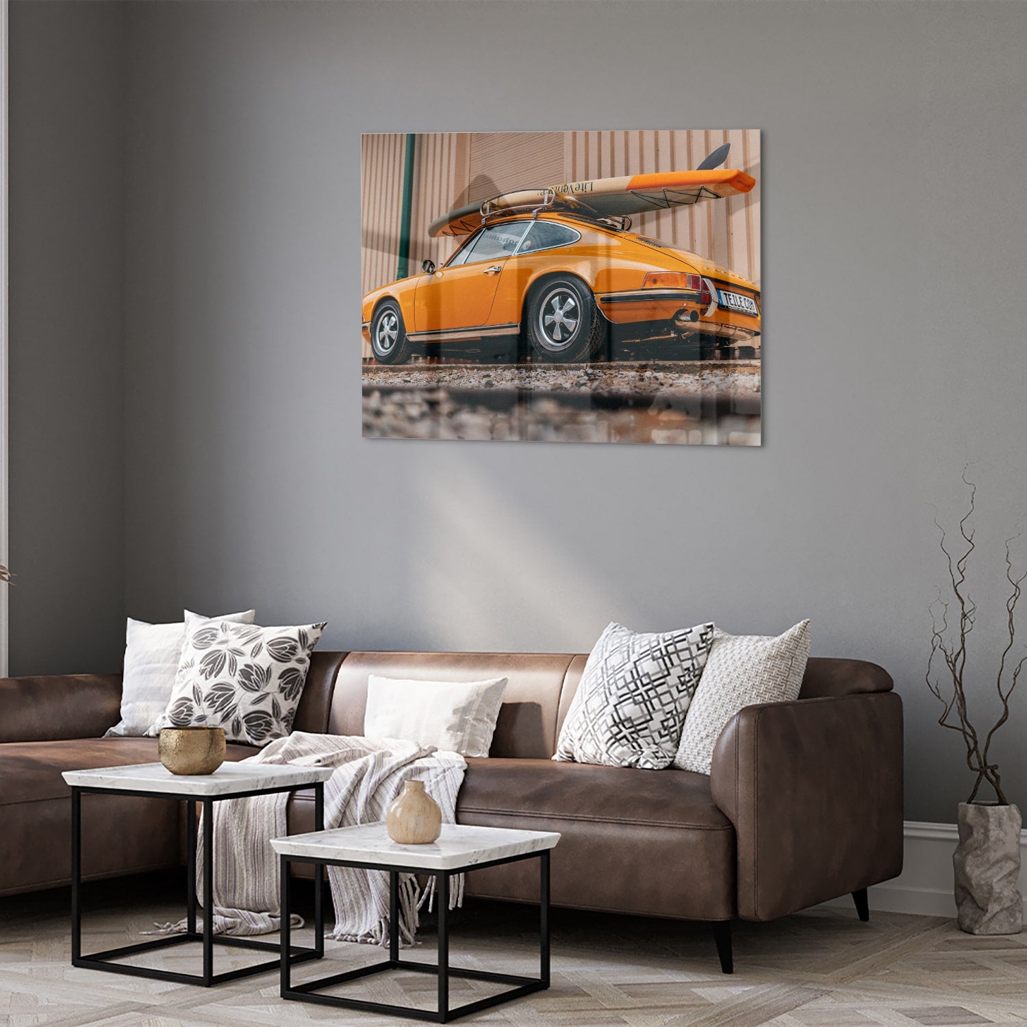 Een glazen schilderij van een oranje auto met een surfbord op het dak, gepresenteerd in een moderne woonkamer.