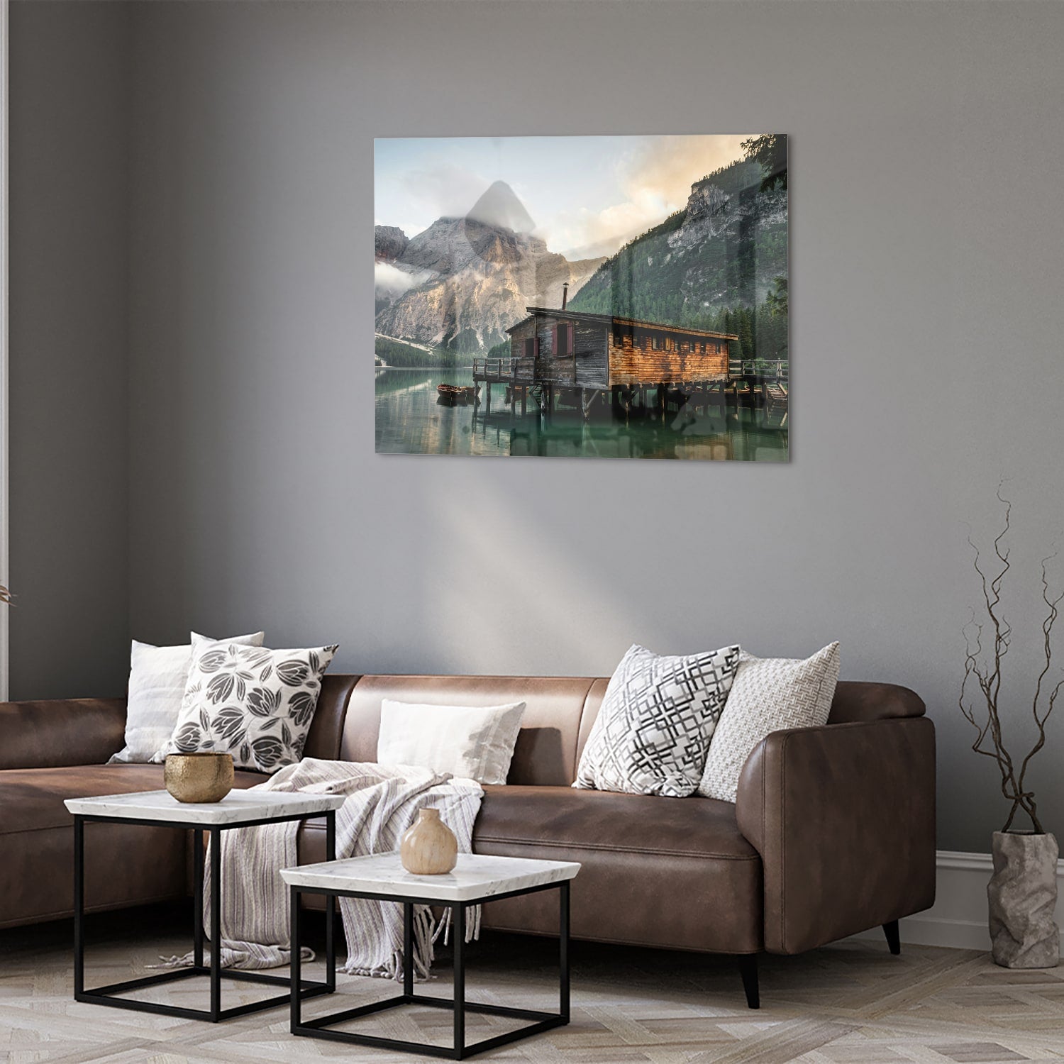 Glazen schilderij van een berghut aan een kalm meer met bergen op de achtergrond.