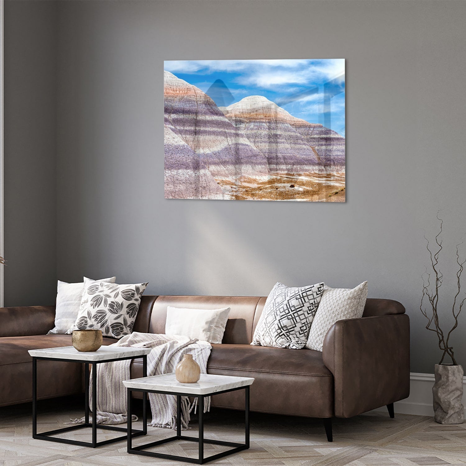 Glazen schilderij van bergen met een blauwe lucht in een moderne woonkamer.