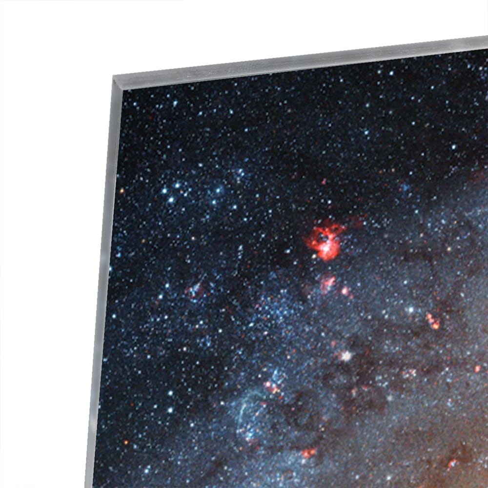 Glazen schilderij van een sterrenstelsel aan de muur in een lichte woonkamer.