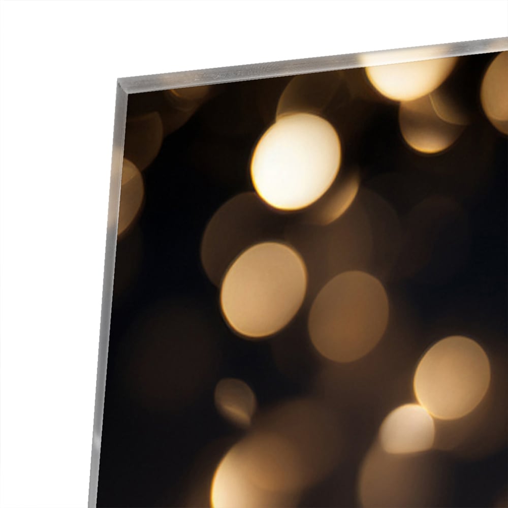Glazen schilderij met gouden bokeh-effect aan de muur in een moderne woonkamer.
