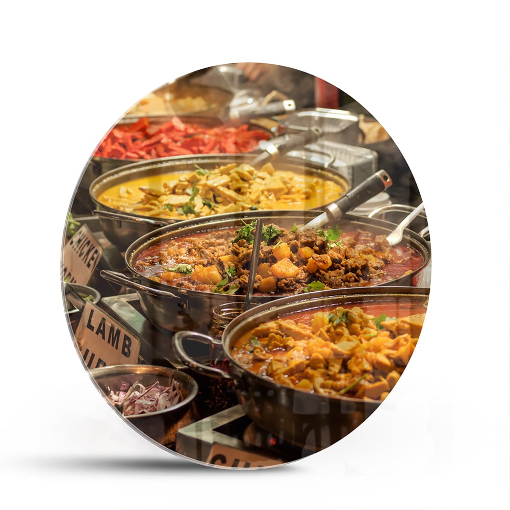 Glazen schilderij met een kleurrijke selectie van Indiaas eten, waaronder lamsvlees en groenten.