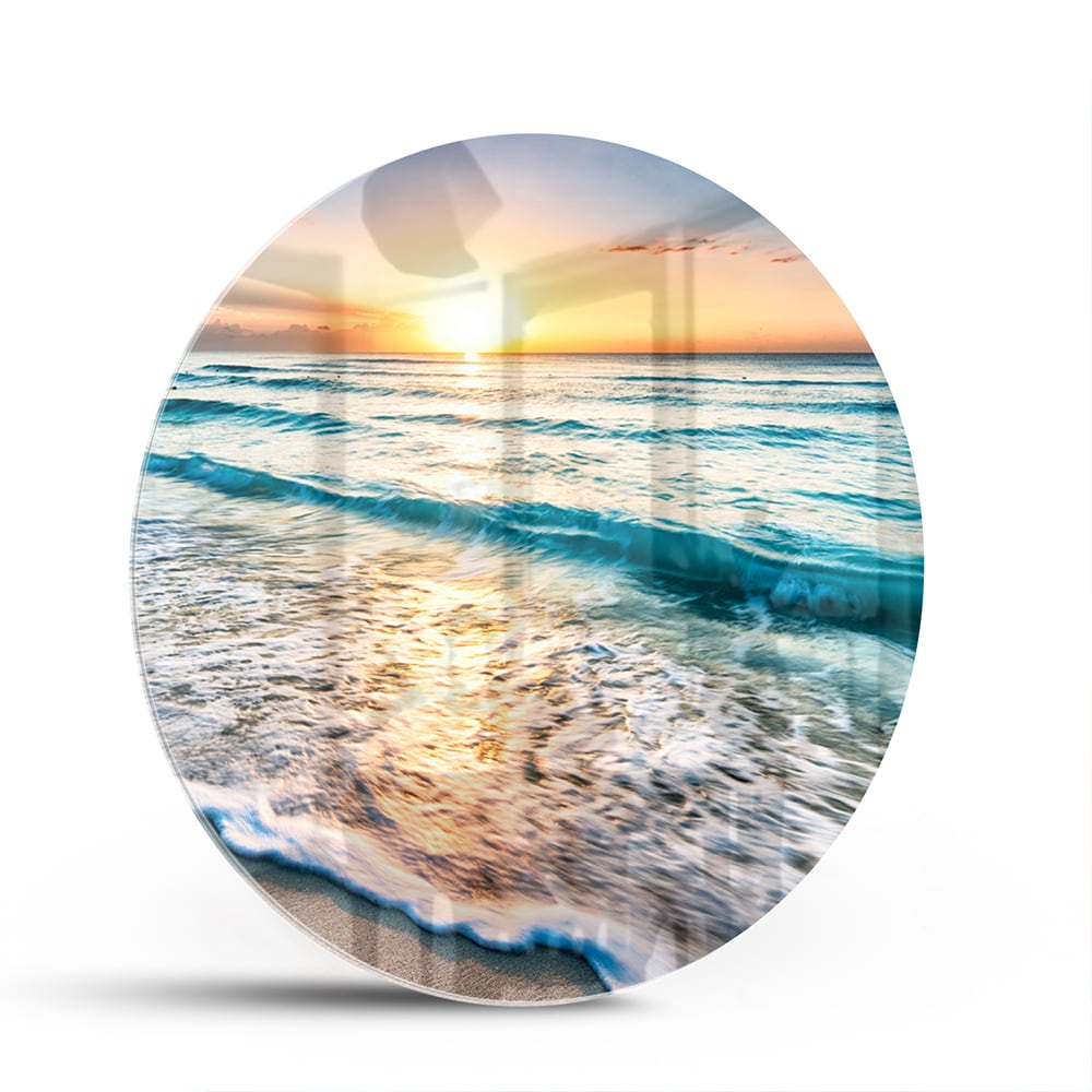 Glazen schilderij van een zonsondergang boven de zee, met kalme golven en zand.