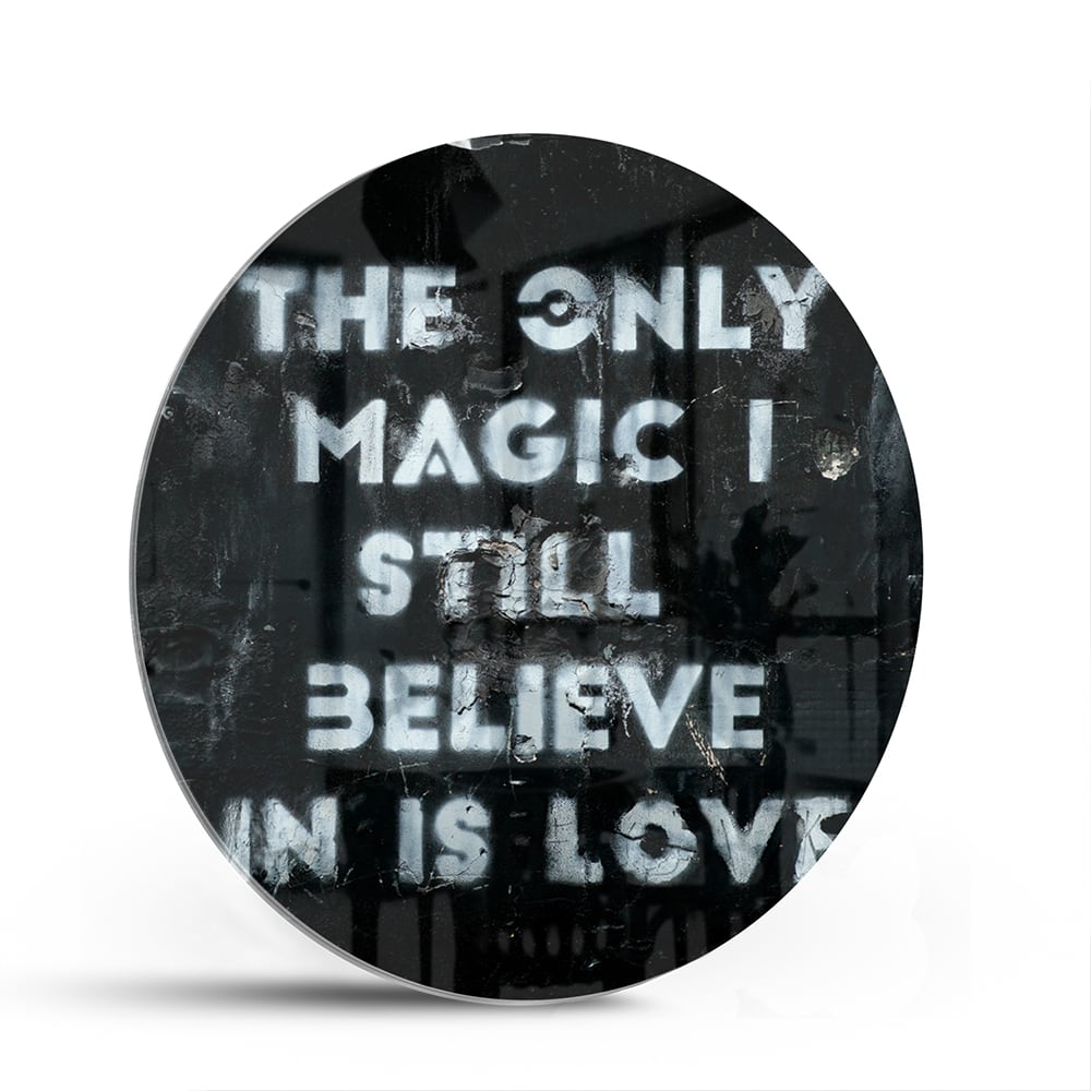Glazen schilderij met de tekst 'The only magic I still believe in is love', hangt aan de muur in een lichte woonkamer.