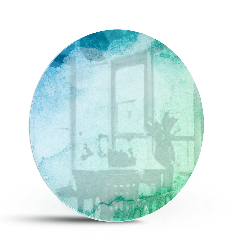 Abstract glazen schilderij in diverse tinten blauw en groen aan de muur.