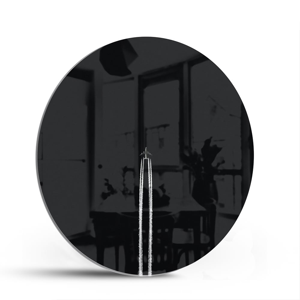 Zwart glazen schilderij aan de muur in een moderne woonkamer met houten meubel.