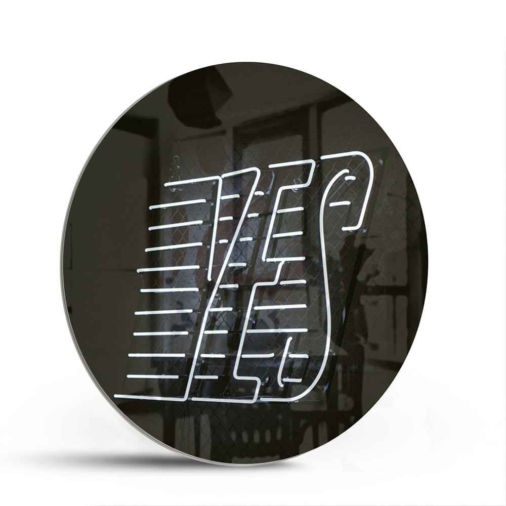Glazen schilderij met 'YES' text in zwart en wit, hangend aan de muur.