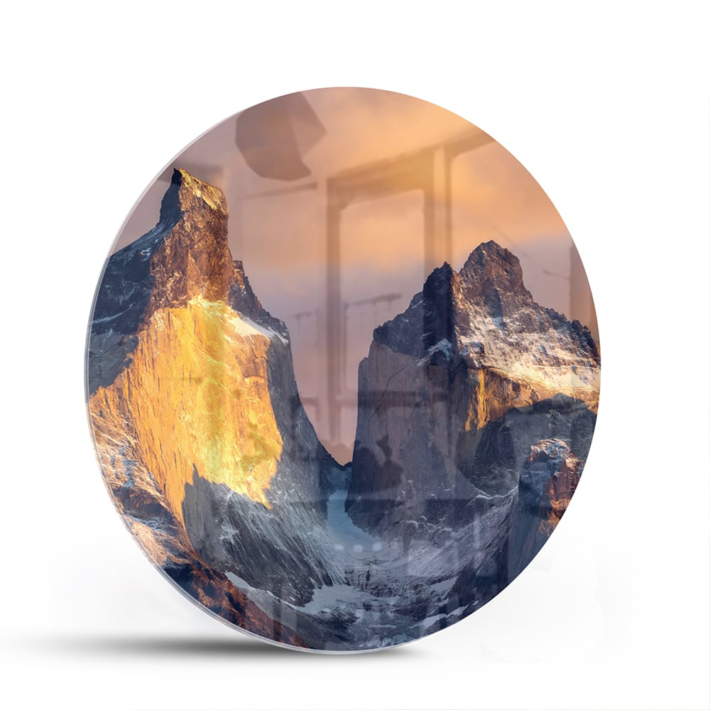 Een glazen schilderij van majestueuze bergen met gouden ochtendlicht