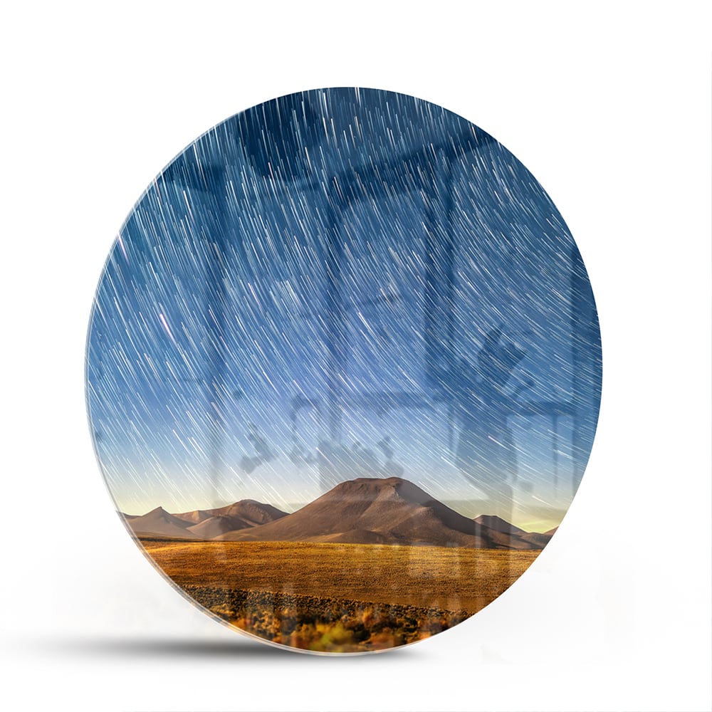 Glazen schilderij met sterrenhemel boven bergen, hangend aan de muur.