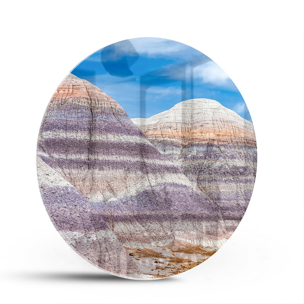 Glazen schilderij van bergen met een blauwe lucht in een moderne woonkamer.