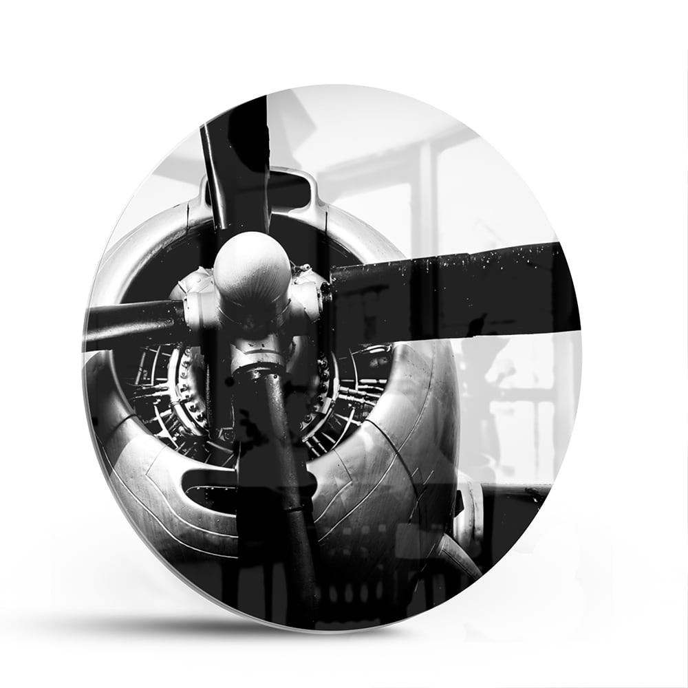 Zwart-wit glazen schilderij van een vintage vliegtuigpropeller tegen een lichte muur.