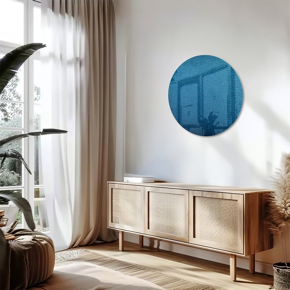Blauw glazen schilderij met reflecties aan de muur in een moderne woonkamer.