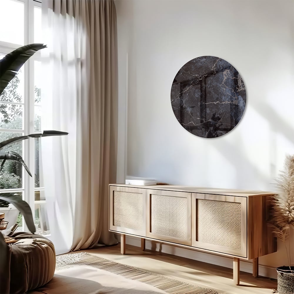 Glazen schilderij met donker marmerlook aan een lichte muur in een moderne woonkamer.